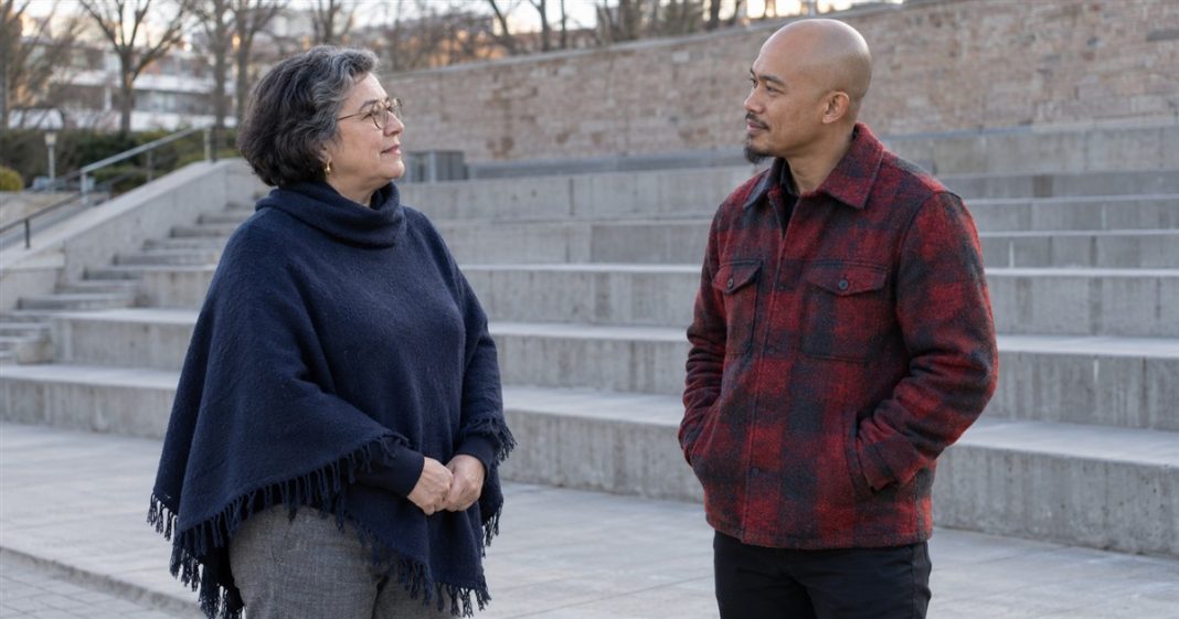 Dating pace: brief public conversation — realistic cover 20261005 A woman in a navy poncho and a man in a red plaid jacket talking beside outdoor concrete seating steps.
