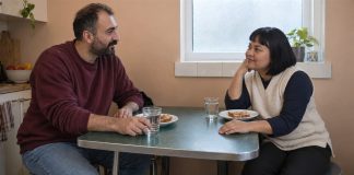 Two adults listening to each other over toast and water at a green kitchen table.