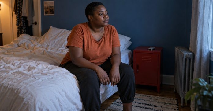 Energy boundaries quiet bedroom realistic cover 3616 A woman in an orange shirt sits quietly on the edge of a bed, with a small closed phone on a red bedside cabinet.