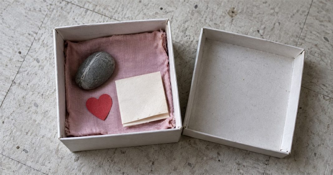 Love Box — Realistic Simple Keepsake Open cardboard keepsake box with pink cloth, a smooth stone, red paper heart and folded note