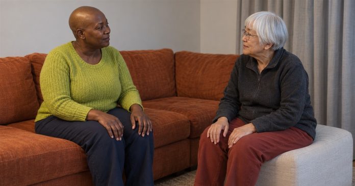Two women having a quiet conversation beside an orange sofa and cream ottoman