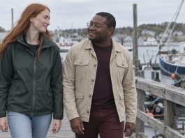 Two adults smiling at each other while walking along a harbor boardwalk