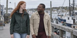 Two adults smiling at each other while walking along a harbor boardwalk