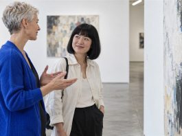 Two women discussing an abstract painting in a contemporary art gallery