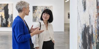 Two women discussing an abstract painting in a contemporary art gallery