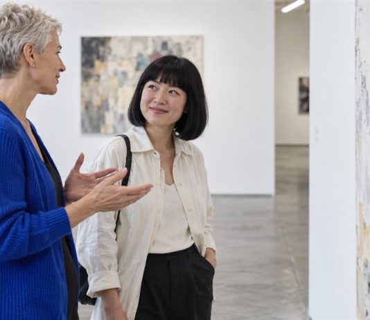 Two women discussing an abstract painting in a contemporary art gallery