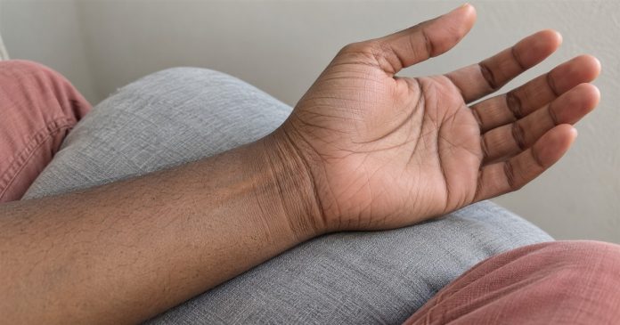 Psychic888 realistic wrist observation 4147 Relaxed palm-up hand and inner wrist resting on a gray cushion, showing natural skin creases.